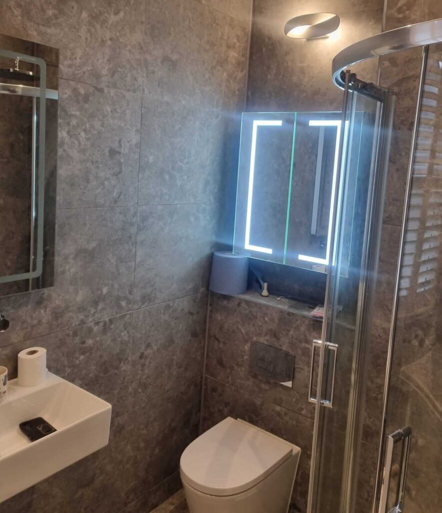 Premium close-up of a wall-mounted sink and an intelligent LED mirror by Karl Andy Plumbing.