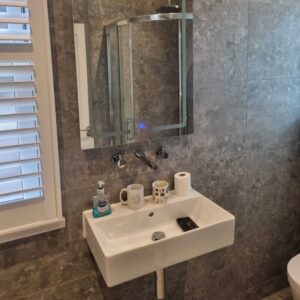 Modern wall-mounted bathroom sink and vanity mirror installed by Karl Andy Plumbing.