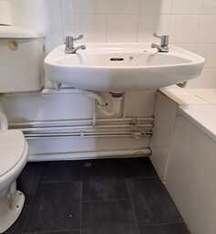 Dated bathroom with visible piping before renovation by Karl Andy Plumbing.
